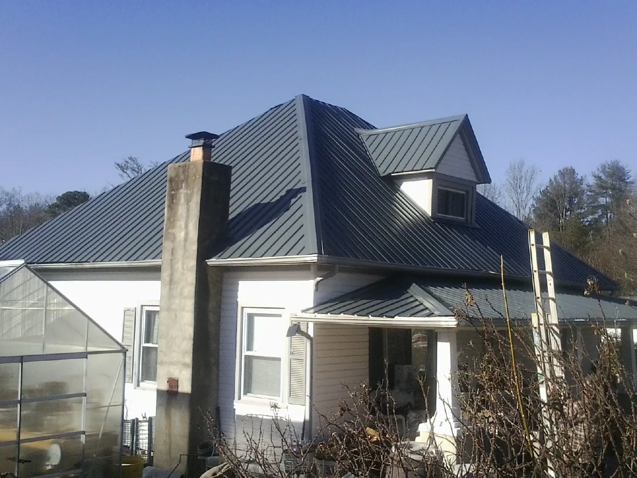 Dark blue standing seam metal roof on a white farmhouse with dormer — Slate & Tile Roof Repair by Roofing Brothers in Canyon Country