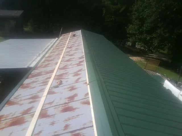 Old rusted panels beside newly installed green metal roofing — Wind Damage Roof Repair by Roofing Brothers in Canyon Country