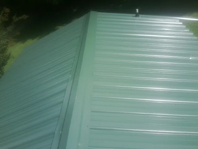 New green metal panels meeting at the ridge of a roof — Flat Roof Repair work by our crew in Canyon Country