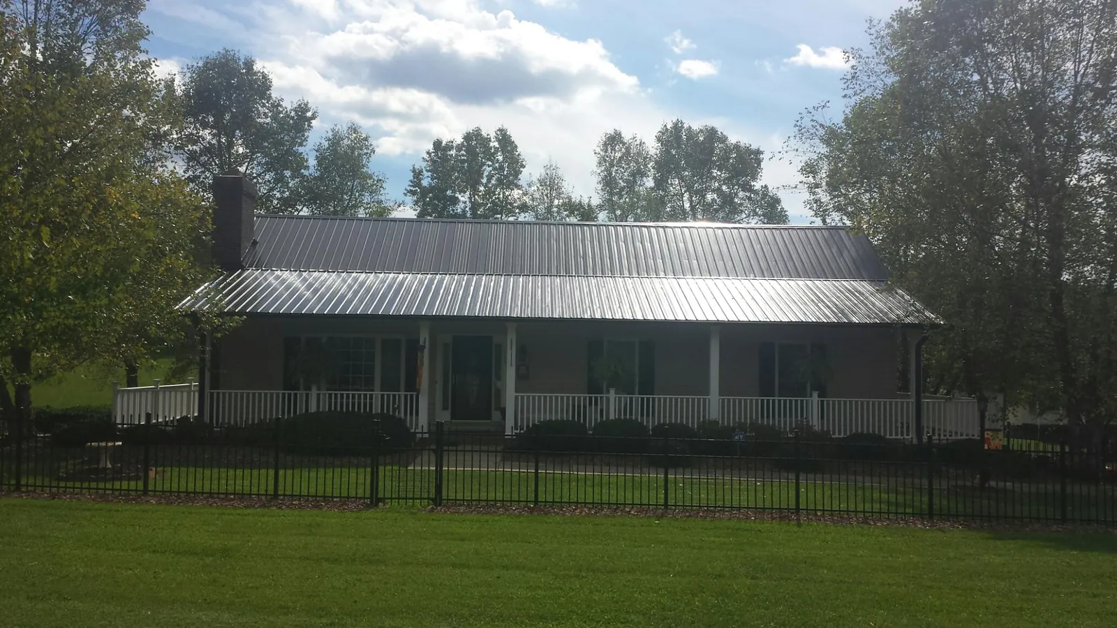 Gray metal roof on a brick ranch with a full width front porch — Gutter Guard Installation work by our crew in Canyon Country