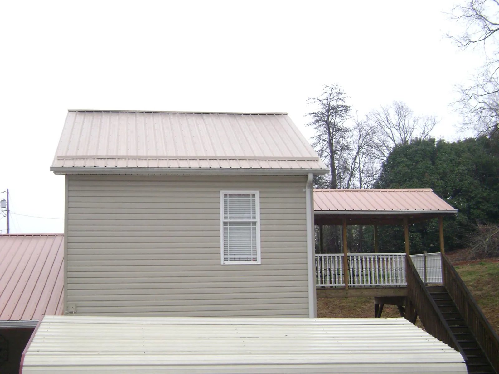 Tan metal roofs on a two story addition and attached porch, from a Roof Replacement job in Canyon Country