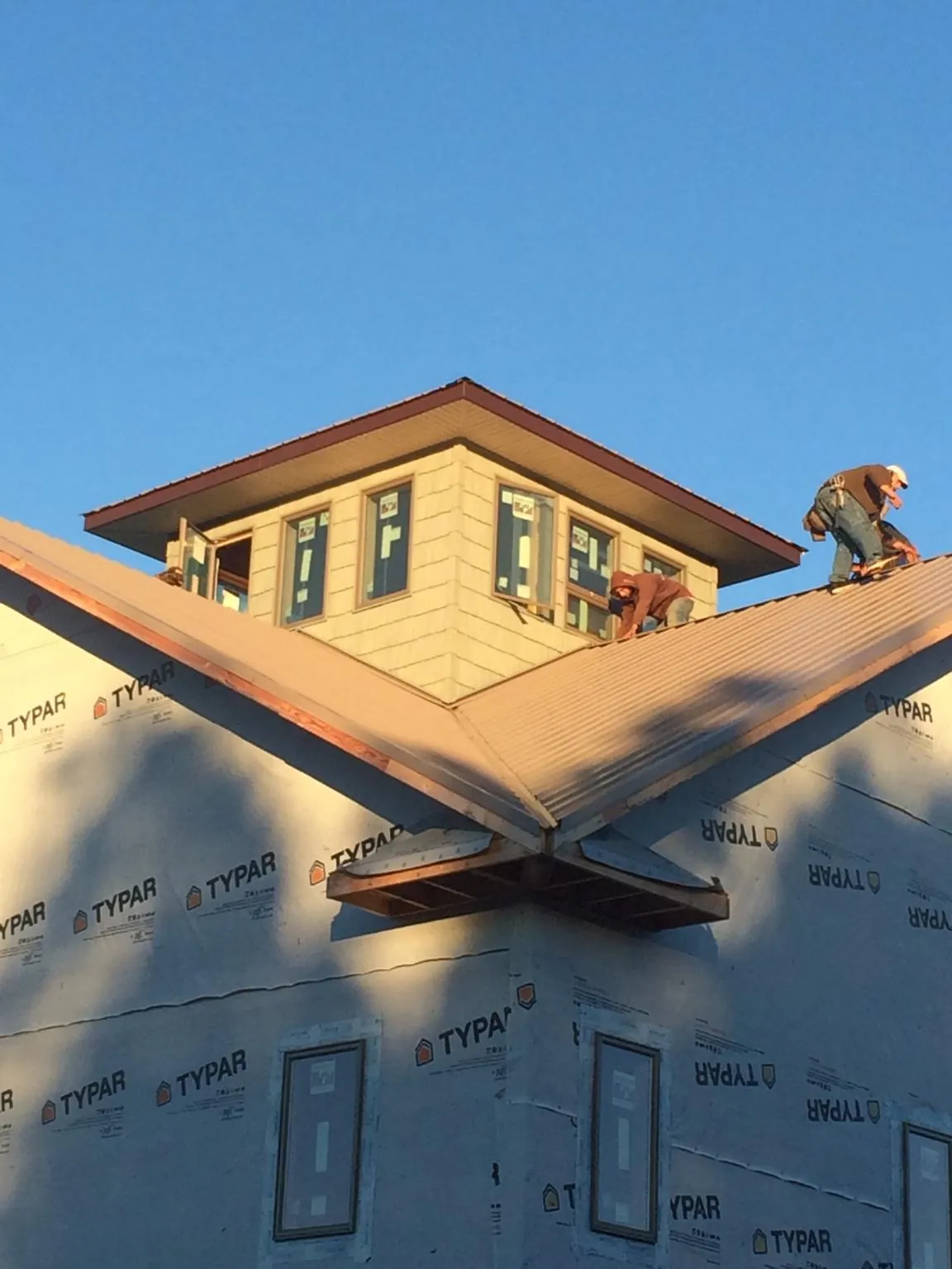 Roofers working around a rooftop cupola on a new metal roof at sunset — Roof Waterproofing in Canyon Country by Roofing Brothers